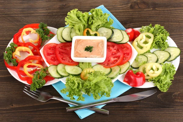 Pokrojone warzywa i sosem na talerzu na drewnianym stole — Zdjęcie stockowe