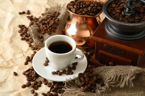 Cup of coffee, pot and grinder on beige background — Stock Photo, Image