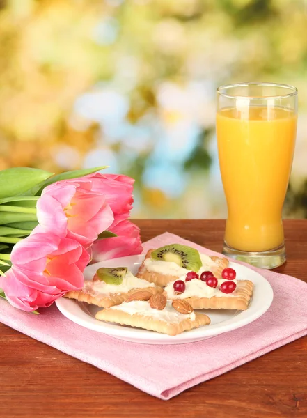 Tasty canapes with cheese, kiwi and cranberry, almond, on color plate, on bright background — Stock Photo, Image