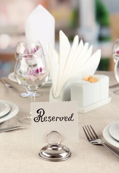 Reserved sign on restaurant table with empty dishes and glasses — Stock Photo, Image