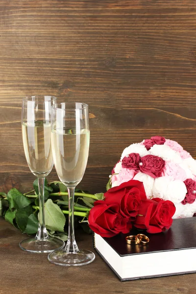 Vigselringar på Bibeln med rosor och glas champagne på trä bakgrund — Stockfoto