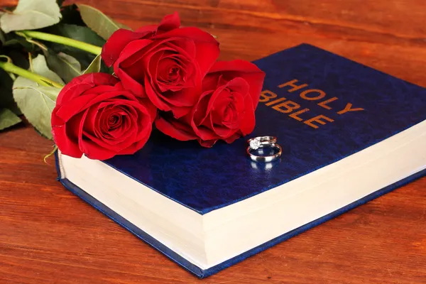 Obrączki na Biblii z róż na drewniane tła — Zdjęcie stockowe