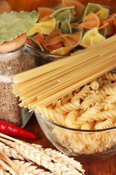 Verschillende soorten pasta, kruiden, tomaten op een houten tafel — Stockfoto