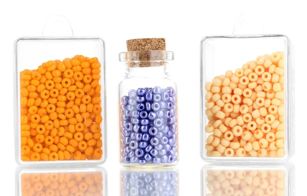 Bunte Perlen stapeln sich in Schachteln und Glasflaschen isoliert auf weiß — Stockfoto