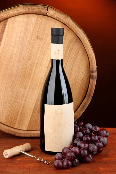 开瓶器和一瓶红酒、 葡萄、 木桶木制桌上黑的背景上的组成 — 图库照片
