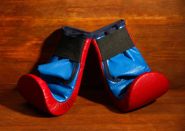 Small children boxing gloves on wooden background — Stock Photo, Image