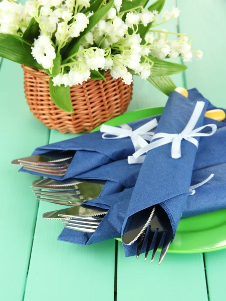 Garfo e faca envolto em guardanapo de papel azul, na cor de fundo de madeira — Fotografia de Stock