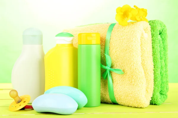 Cosméticos para bebés, jabón y toallas sobre mesa de madera, sobre fondo verde —  Fotos de Stock