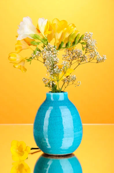 Belo buquê de freesia em vaso no fundo laranja — Fotografia de Stock