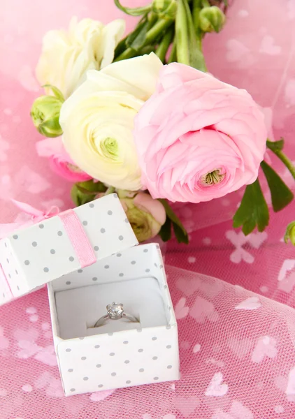 Ranunculus (tazas de mantequilla persa) y anillo de compromiso, en tela rosa —  Fotos de Stock