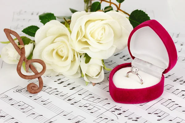 Treble clef, roses and box holding wedding ring on musical background — Stock Photo, Image