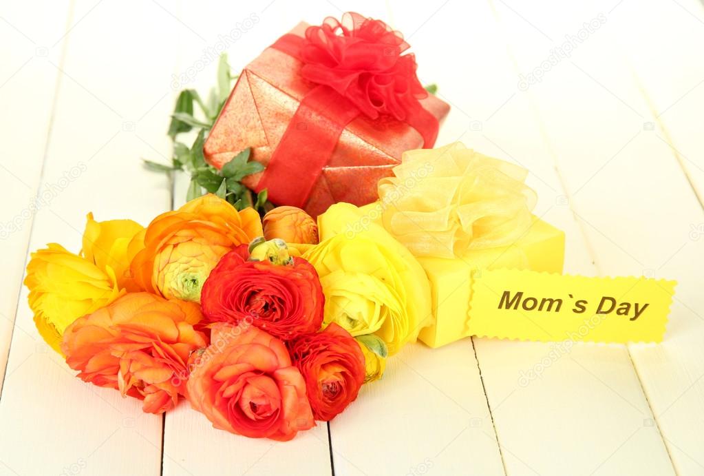 Ranunculus (persian buttercups) and gifts for mothers day, on white wooden background