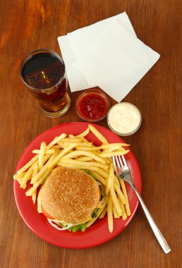 patates kızartması ve ahşap zemin üzerinde soğuk içecek ile lezzetli peynirli burger