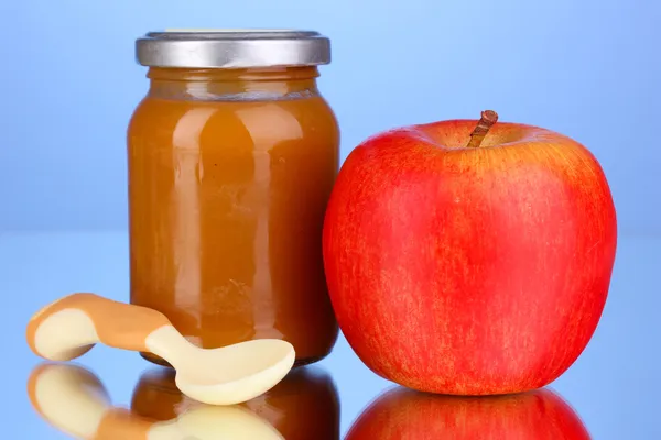 Полезное и вкусное детское питание с яблоком и ложкой на синем фоне — стоковое фото