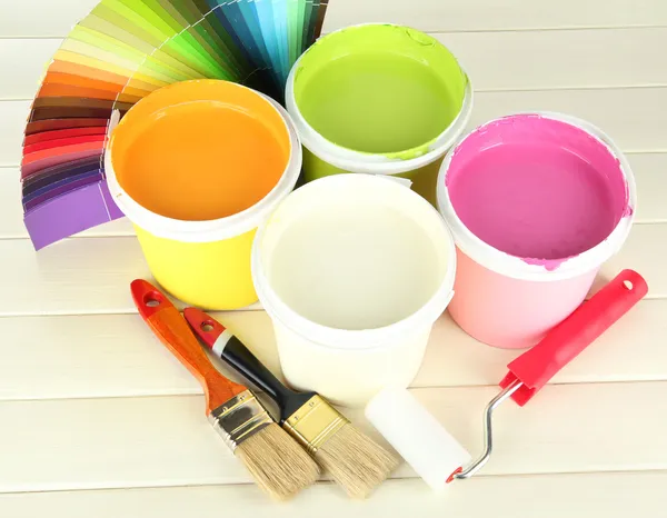 Набор для покраски: горшки, кисти, ролики для краски на белом деревянном столе — стоковое фото