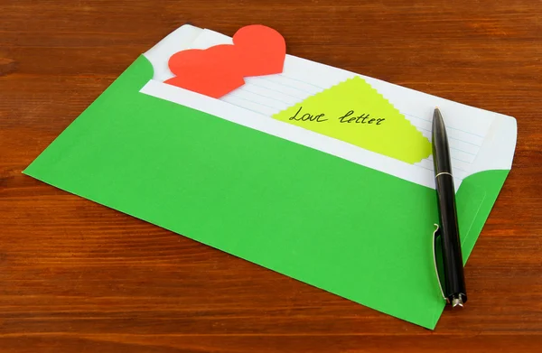 Заметка в конверте с ручкой на деревянном фоне — стоковое фото