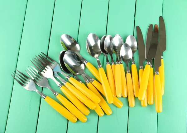 Forks, knives, spoons on color wooden background — Stock Photo, Image