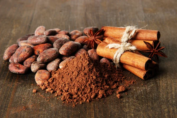 Cocoa beans, cocoa powder and spices on wooden background — Stock Photo, Image