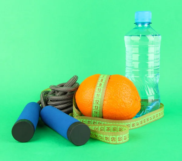 Orange with measuring tape,skipping rope and bottle of water, on color background — Stock Photo, Image
