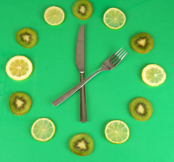 Clock made of kiwi, lime and lemon slices, on color background — Stock Photo, Image