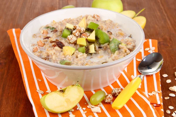 Harina de avena útil en un tazón con fruta en una mesa de madera — Foto de Stock