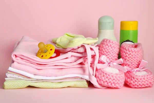 Montón de ropa de bebé sobre fondo rosa — Foto de Stock