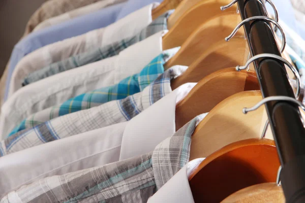 Camisas masculinas em cabides no fundo cinza — Fotografia de Stock