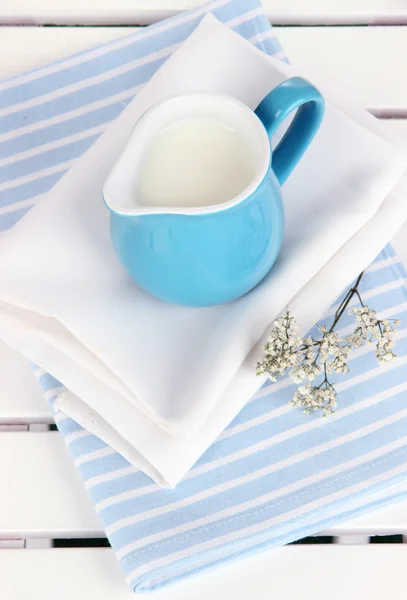 Brocca blu con latte su tovagliolo su tavolo da picnic in legno primo piano — Foto Stock