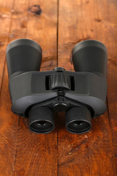 木制背景上的黑色现代双筒望远镜 — 图库照片