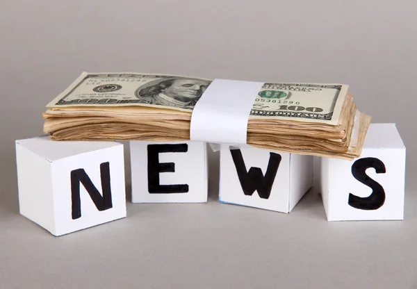 Biała Księga kostki oznaczone "News" z pieniędzy na szarym tle — Zdjęcie stockowe
