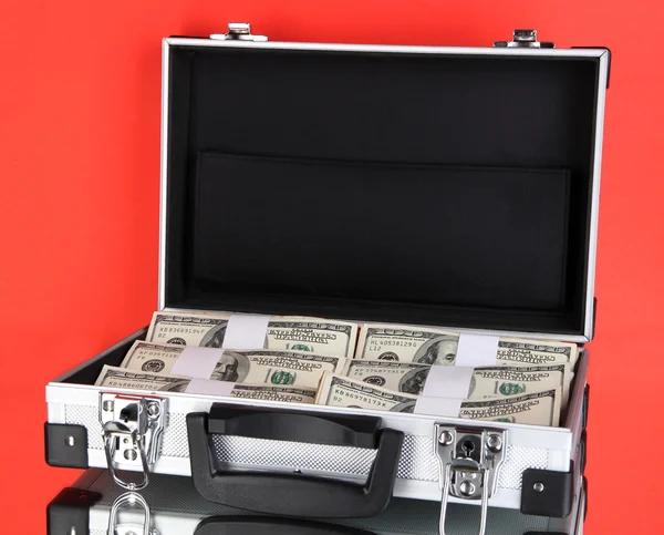 赤い背景の上の 100 ドル紙幣のスーツケース — ストック写真