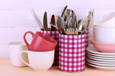 Cups, bowls nd other utensils in metal containers isolated on light background