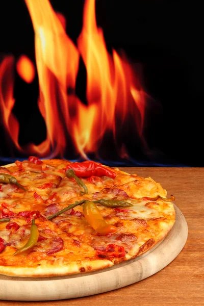 Leckere Pfefferoni-Pizza auf Holzbrett auf Flammenhintergrund — Stockfoto