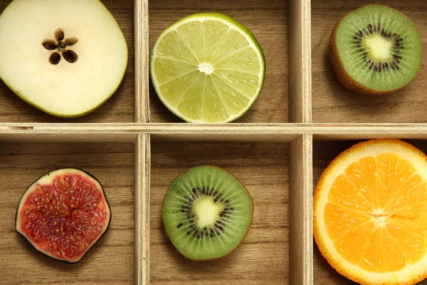Sliced fruits in wooden box background — Stock Photo, Image