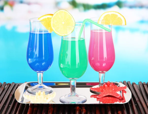 Glasses of cocktails on table near pool — Stock Photo, Image