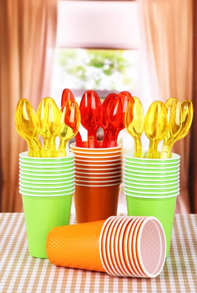 Cups, spoons and forks, of different colors on bright background — Stock Photo, Image