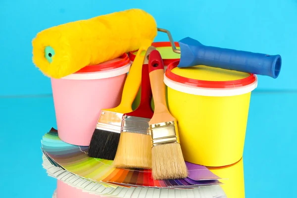 Set for painting: paint pots, brushes, paint-roller, palette of colors on blue background — Stock Photo, Image