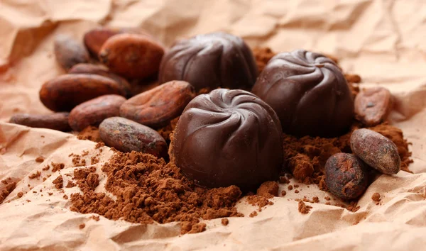 Samenstelling van chocolade snoepjes en cacao op bruine achtergrond — Stockfoto