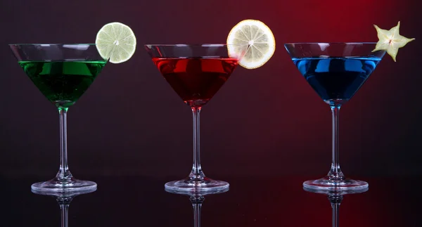 Alkoholische Cocktails in Martinigläsern auf dunkelrotem Hintergrund — Stockfoto