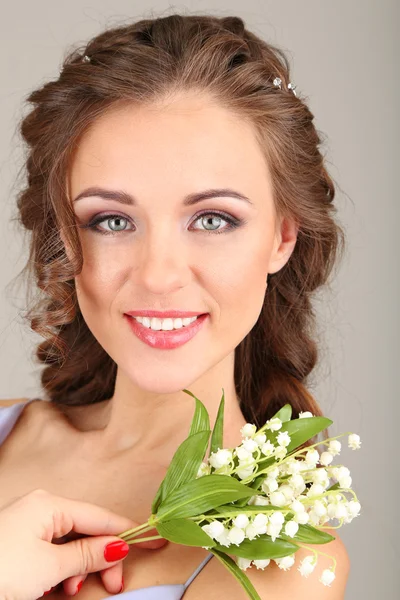 아름 다운 헤어스타일와 회색 배경에 꽃, 젊은 여자 — 스톡 사진