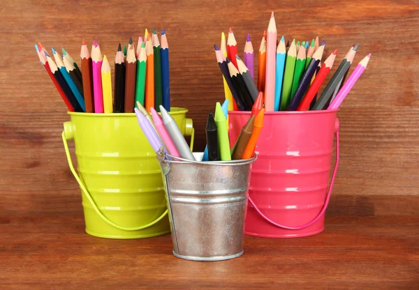 Lápices de colores en tres cubos sobre fondo de madera —  Fotos de Stock