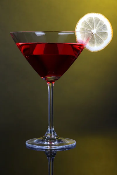 Red cocktail in martini glass on dark yellow background — Stock Photo, Image
