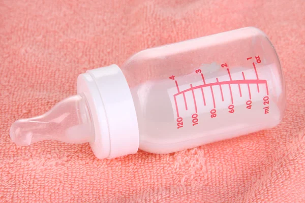 ピンクのタオルの背景にミルクのボトル — ストック写真