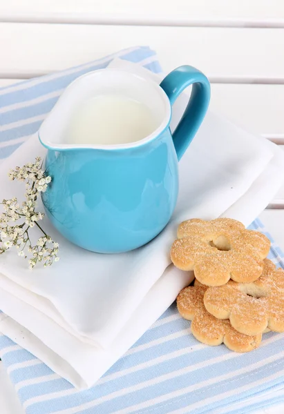 Blue jug with milk and cookies on wooden picnic table close-up — Stock Photo, Image