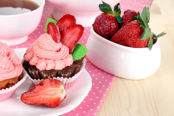 Beautiful strawberry cupcakes and flavored tea on dining table close-up — Stock Photo, Image