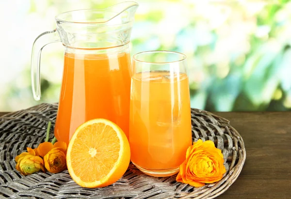 Glas en werper sinaasappelsap op houten tafel, op groene achtergrond — Stockfoto