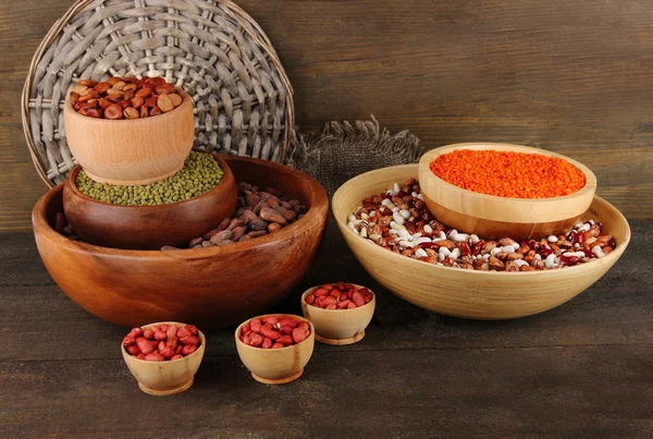 Different kinds of beans in bowls on wooden background — Stock Photo, Image