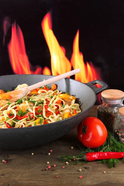 Nudlar med grönsaker på wok på brand bakgrund — Stockfoto