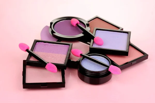 Sombras de olhos brilhantes e escovas de esponja para fundação em fundo rosa — Fotografia de Stock