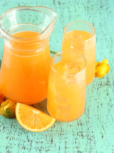 眼镜和投手的橙汁在蓝色木制背景 — 图库照片